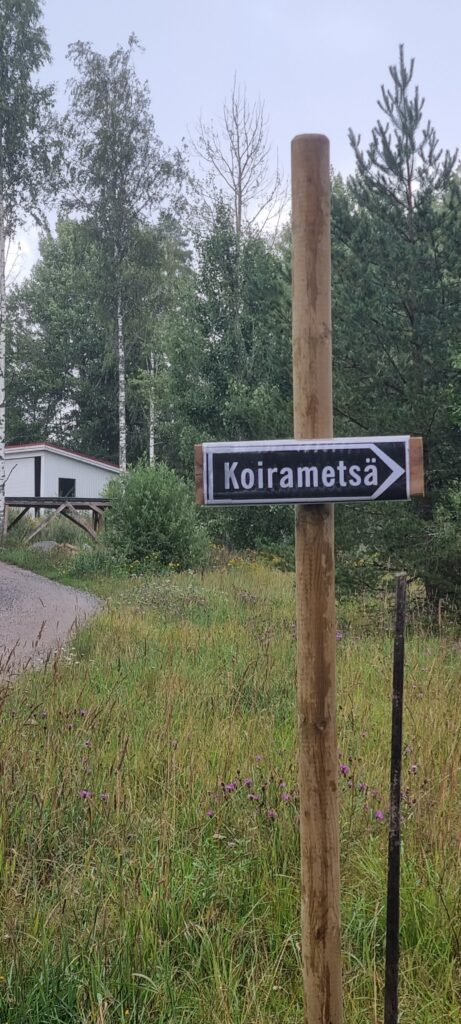 Tienvarsikyltti, jossa lukee Koirametsä ja nuoli metsätielle